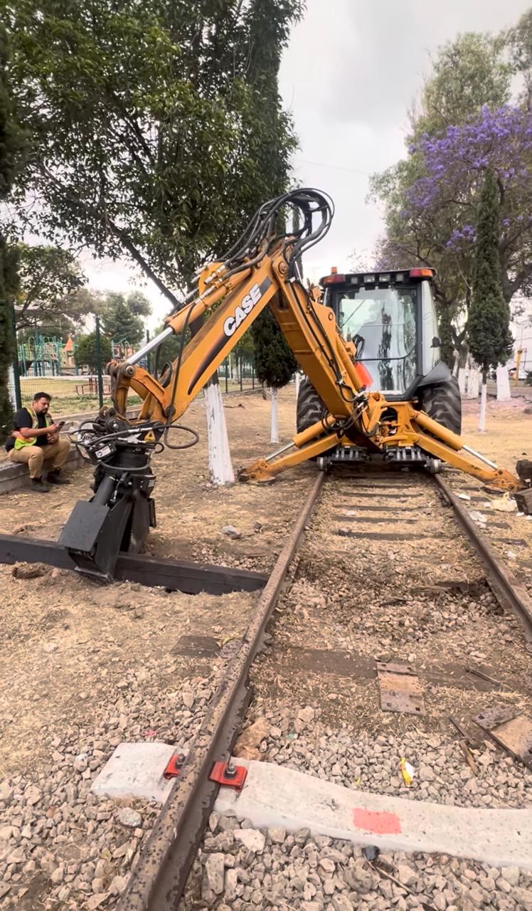 Retroexcavadora hi-rail con pinzas trabajando sobre riel ferroviario